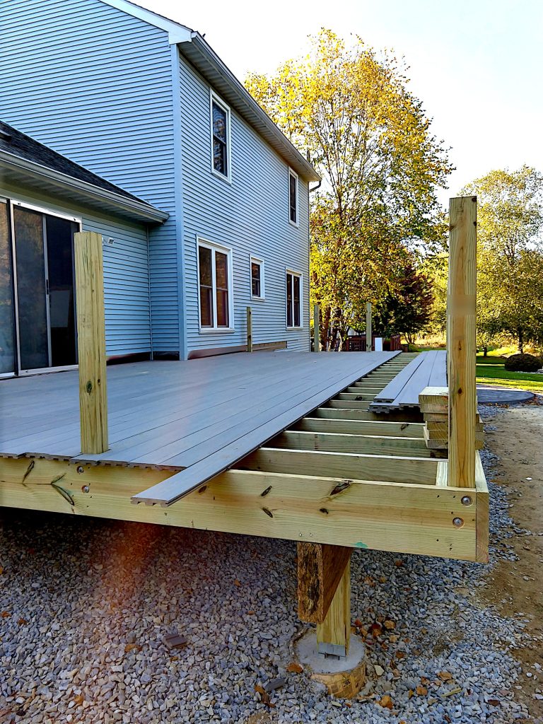 Partially built wooden deck with composite decking boards being installed on a residential home.