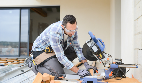 Professional contractor cutting wood with a miter saw during a deck installation project