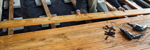 A homeowner installing a wooden deck with tools and fasteners, ensuring a smooth and secure deck installation.